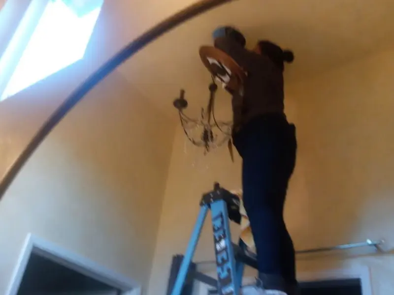 Electrician installing a chandelier in a Running Springs residence